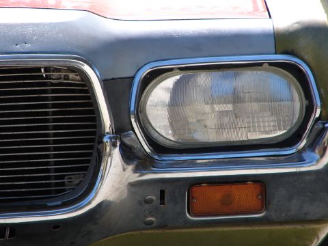 1973 Ford Ranchero - The front of a vehicle is captured in this close-up shot, highlighting its headlight and grille details.