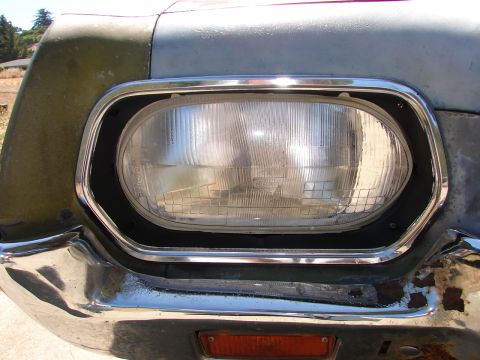 1973 Ford Ranchero - Close-up of a vehicle's front end, revealing a damaged headlight and bumper assembly.