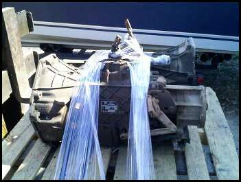 1989 Ford Bronco - A transmission assembly is wrapped in plastic and secured to a wooden pallet.