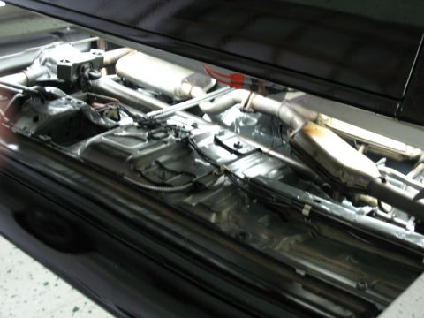 1985 Mercury Cougar - The underside of a black vehicle shows its exhaust system and rear differential.