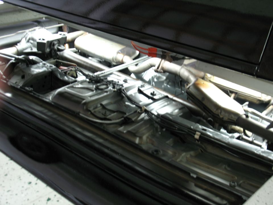 Undercarriage of a black car with exhaust pipes and differential visible