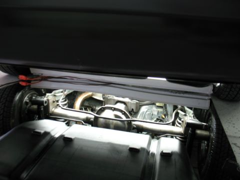1985 Mercury Cougar - Underside view of a vehicle's rear axle and exhaust system, "SUPERMOTORS" branding.