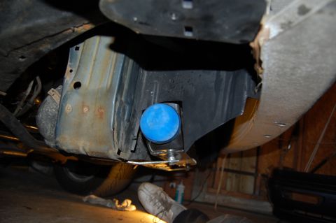 1985 Mercury Grand Marquis - Close-up view of a car's undercarriage, showing a blue bumper mount and rusty metal components.