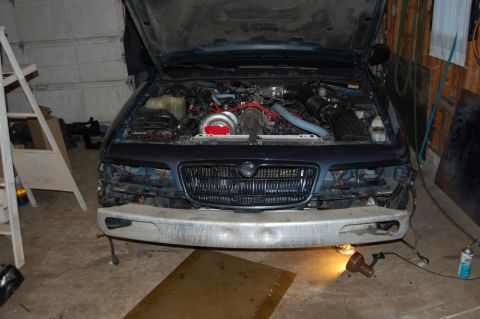 1985 Mercury Grand Marquis - The engine bay of a blue Mercury Grand Marquis, modified with a turbocharger and custom intake system, is shown with the hood open.