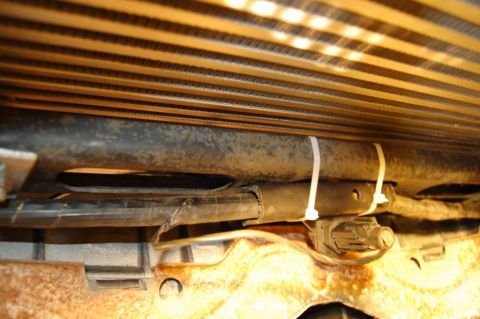 1985 Mercury Grand Marquis - This image shows a close-up view of a vehicle's radiator and associated hoses, with visible wiring and zip-tied wiring.