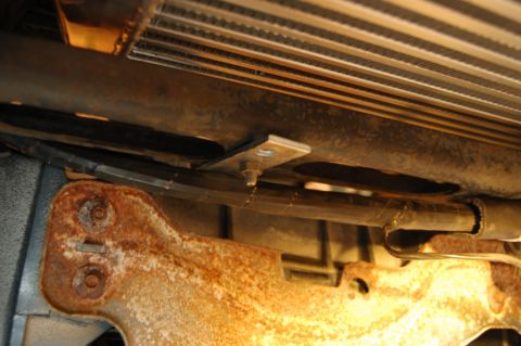 1985 Mercury Grand Marquis - Close-up view of a radiator and hoses, with a rusted bracket visible below.