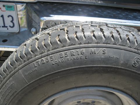 1986 Ford Bronco - A close-up view of a tire and a license plate from a vehicle.