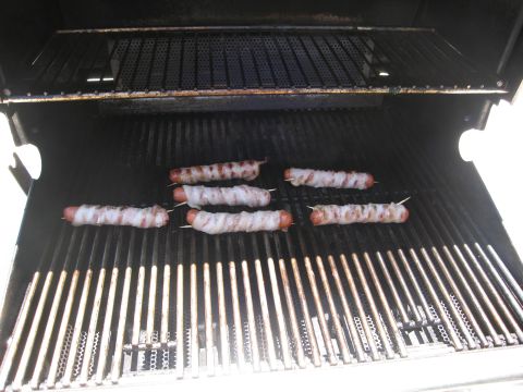 1986 Ford Bronco - Hot dogs wrapped in bacon are cooking on a grill, with a visible Supermotors.net logo in the corner.