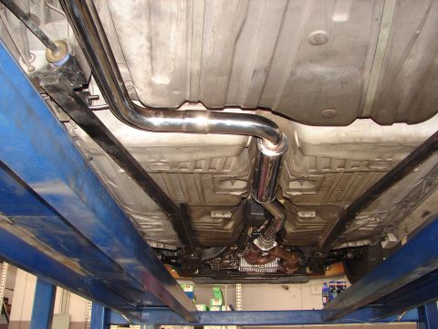 1992 Ford Taurus - A shiny exhaust system and muffler are visible on the undercarriage of a vehicle supported by a car lift.