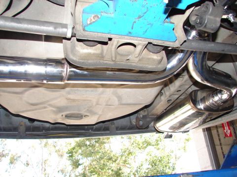 1992 Ford Taurus - Underside view of a vehicle's exhaust system, including a fuel tank and chrome muffler.
