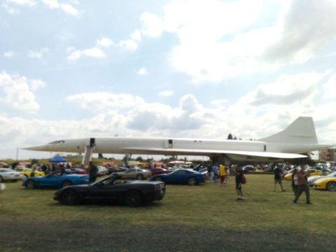 1991 Ford Crown Victoria - A Concorde jet is on display at an outdoor event with several cars parked on the lawn.
