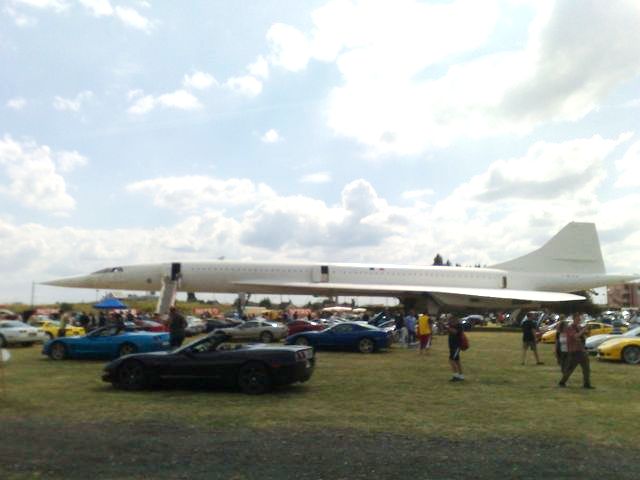 Concorde jet parked on grass with many cars around it
