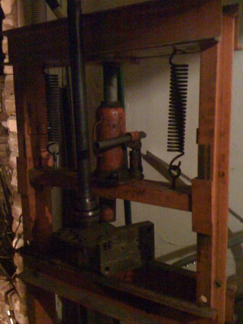 1989 Ford Bronco - A hydraulic press with an orange frame and a red hydraulic jack is shown.