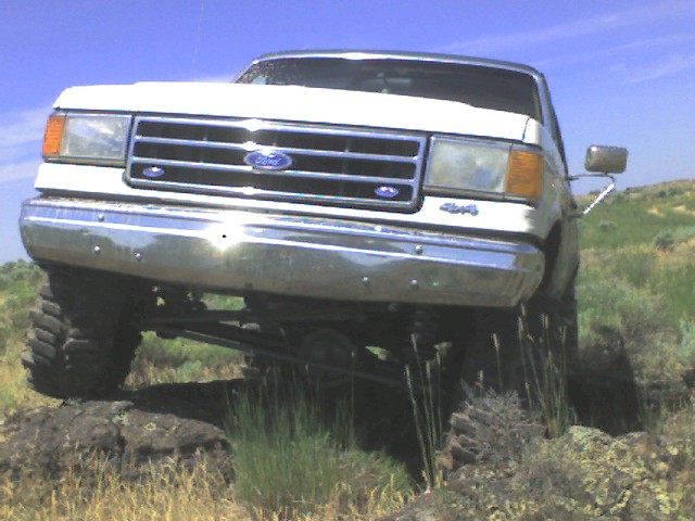 White 1989 Ford Bronco front view with 4x4 badge on rocky terrain