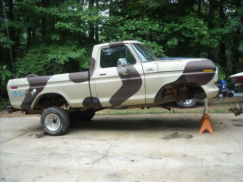 1979 Ford F-150 - A 1979 Ford F-150 pickup truck with a camouflage paint scheme is shown on jack stands, possibly undergoing maintenance or repair.