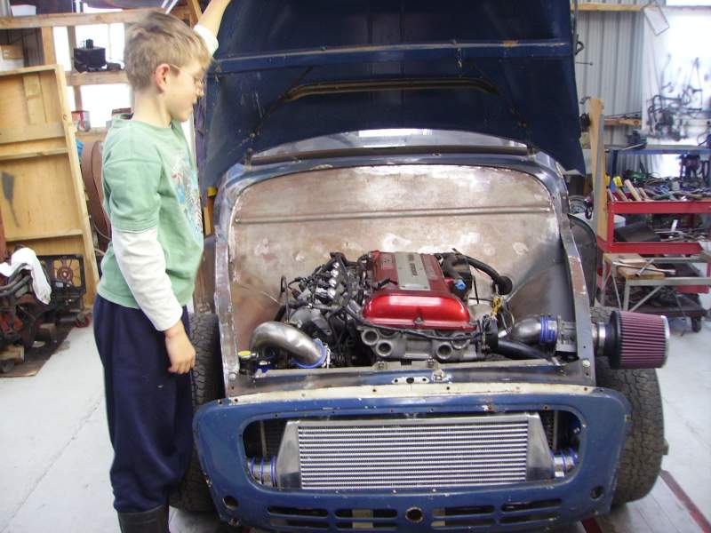 Blue classic Mini engine bay with red cam cover, turbo piping and front-mount intercooler