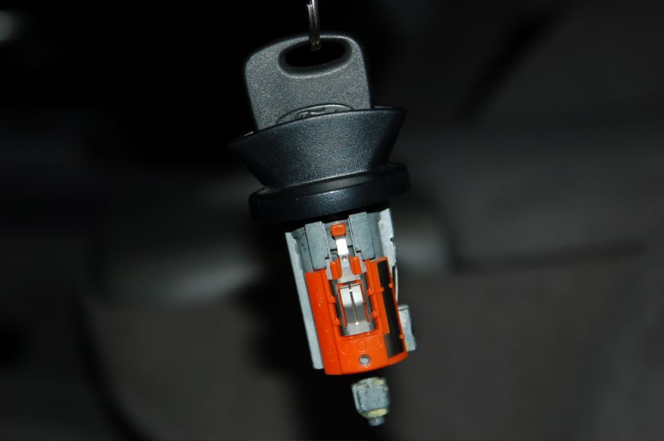 Ignition cylinder with key removed, showing internal mechanism. Orange and gray plastic housing