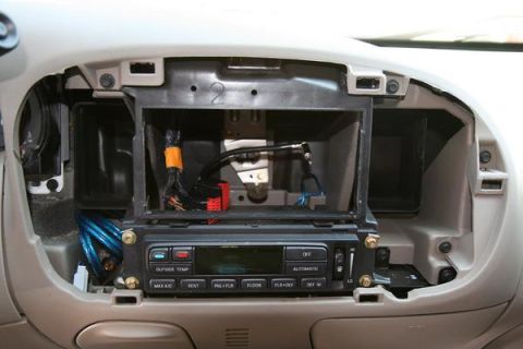 2007 Ford Mustang - The interior of a car shows exposed wiring and climate controls after the radio has been removed.
