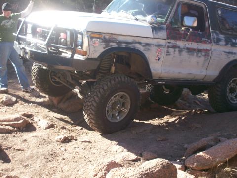 1978 Ford Bronco - This modified SUV is navigating a challenging rocky trail with one wheel lifted.