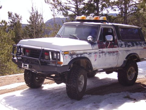 1978 Ford Bronco - This modified Ford Bronco is parked on a snowy, wooded road, ready for off-road adventure.