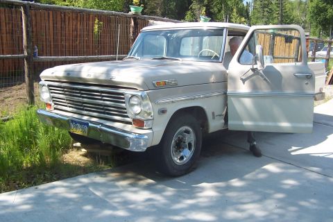 1987 Ford Bronco II - This vintage pickup truck, likely from the late 1960s, is parked on a concrete driveway with its driver's side door open.
