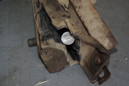 1995 Ford Bronco - A worn suspension part is shown with a nickel lodged inside its damaged structure.
