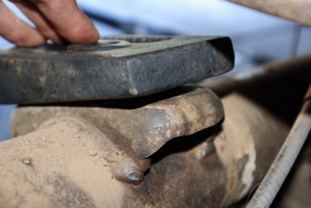 1995 Ford Bronco - A close-up view of a vehicle's suspension part, with a hand holding another component above it.