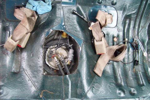 1994 Mazda 626 - Interior view of a car with the fuel pump access panel removed, revealing the fuel pump and seatbelts.