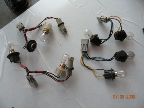 1994 Acura Integra - A collection of assorted automotive light bulbs and their associated wiring harnesses are laid out on a white surface.