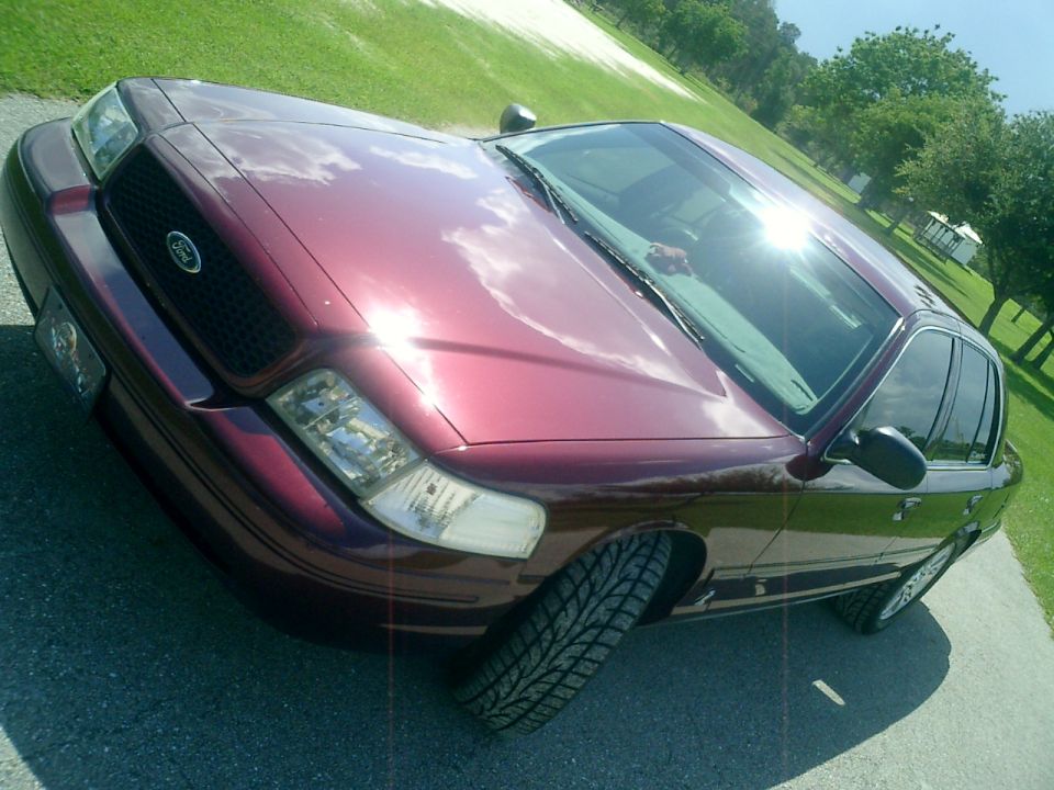Maroon Ford Crown Victoria, front quarter view. The grille and headlights look like a 2004 model
