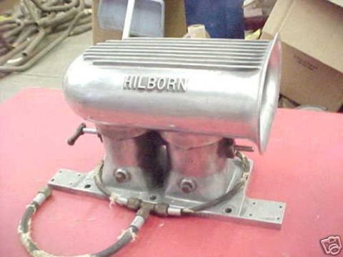 1972 Ford Ranchero - A Hilborn fuel injection unit is shown on a red surface with various parts in the background.
