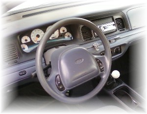 1998 Ford Crown Victoria - The interior of a car shows a custom instrument cluster and a manual transmission shifter.
