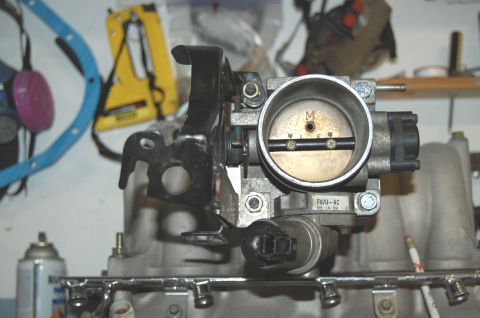 1994 Ford Bronco - A close-up view of a throttle body assembly, likely for an automotive engine, with visible part numbers and a date stamp.
