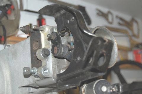 1994 Ford Bronco - Close-up of a throttle body assembly, showing mechanical linkages and a black metal bracket against a blurred background.