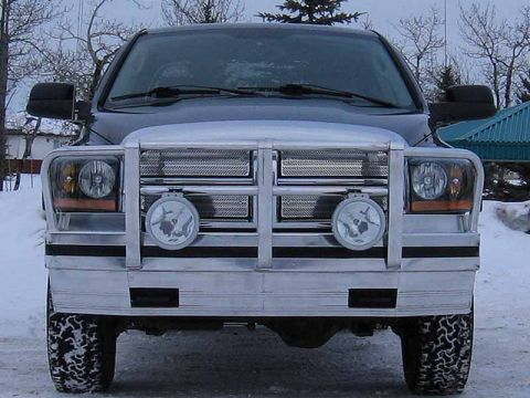 2005 Dodge 3500 - Front view of a dark blue truck with a chrome grille guard and fog lights, parked in the snow.