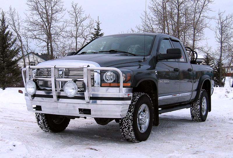 Dark gray pickup truck with chrome grille guard and auxiliary lights in snow