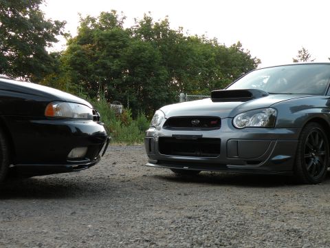 1998 Subaru Legacy - Two Subaru cars, a gray WRX STI and a black Legacy, are parked on a gravel surface.