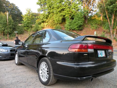 1998 Subaru Legacy - Rear view of a black Subaru Legacy sedan with a spoiler and a license plate visible.