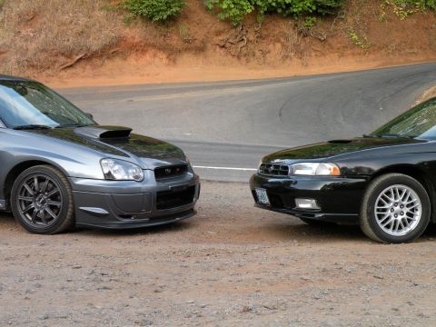 1998 Subaru Legacy - A black 1998 Subaru Legacy is parked next to a gray Subaru WRX STI on a dirt road.