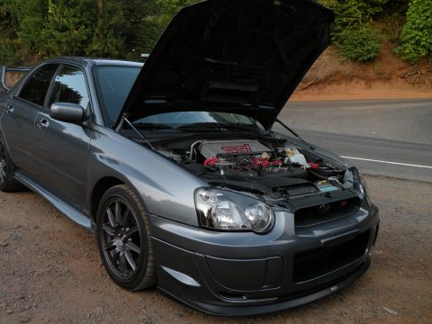 1998 Subaru Legacy - A gray Subaru Impreza WRX STI sedan is parked on a dirt road with its hood open, revealing the engine.