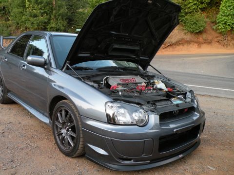 1998 Subaru Legacy - This gray Subaru WRX STI is shown with its hood open, revealing the engine bay. The vehicle is viewed from the front three-quarter angle.