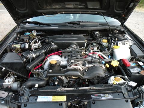 1998 Subaru Legacy - The engine bay of a 1998 Subaru Legacy, the Subaru badge on a sticker.