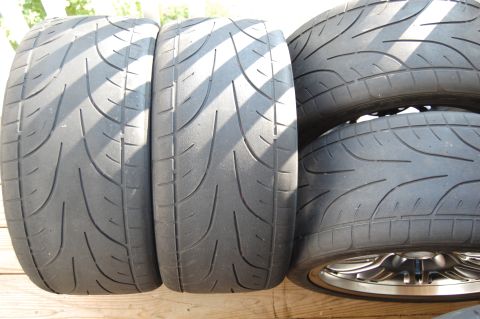 2002 BMW M3 - A collection of four performance tires, some mounted on rims, are displayed on a wooden surface.