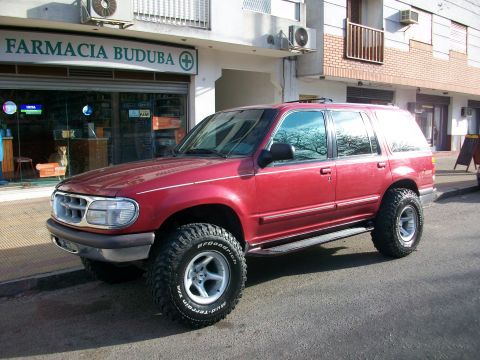 1996 Ford Explorer - This red 1996 Ford Explorer features off-road tires and is parked in front of a pharmacy.