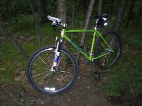1981 Garelli Rally Sport - A green mountain bike rests on a wooded trail, its front wheel prominent in the frame.