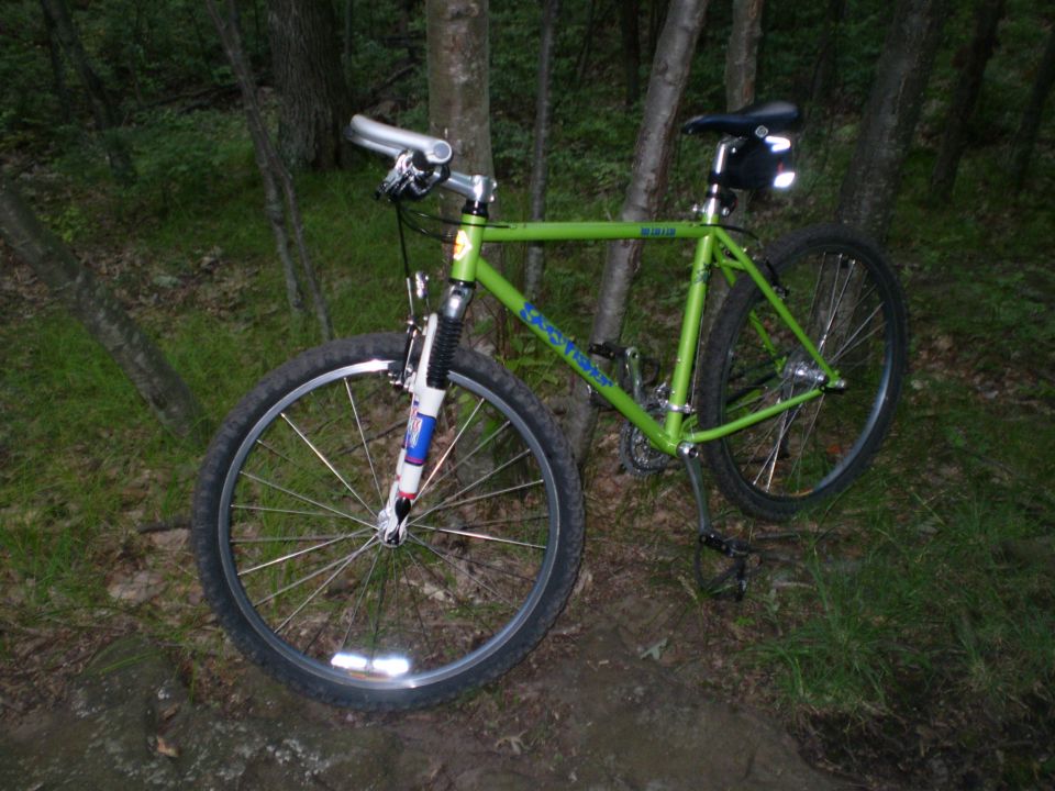 Green mountain bike parked on a trail, front view