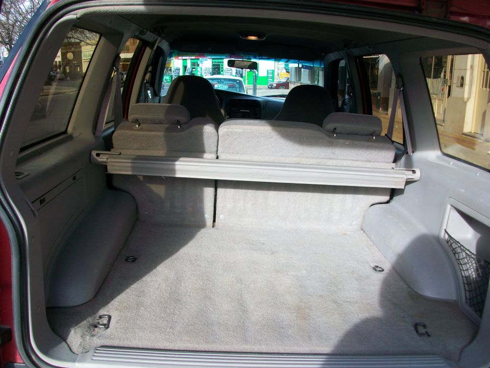 interior cargo area of a red SUV, showing folded rear seats and cargo cover