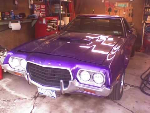 1974 Ford Ranchero - A purple Ford Ranchero is parked in a garage, showing its front grille and headlights.