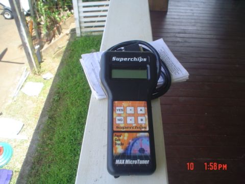 2005 Ford Excursion - A Superchips MAX MicroTuner is shown on a porch railing, with a timestamp indicating it was photographed at 1:58 PM.