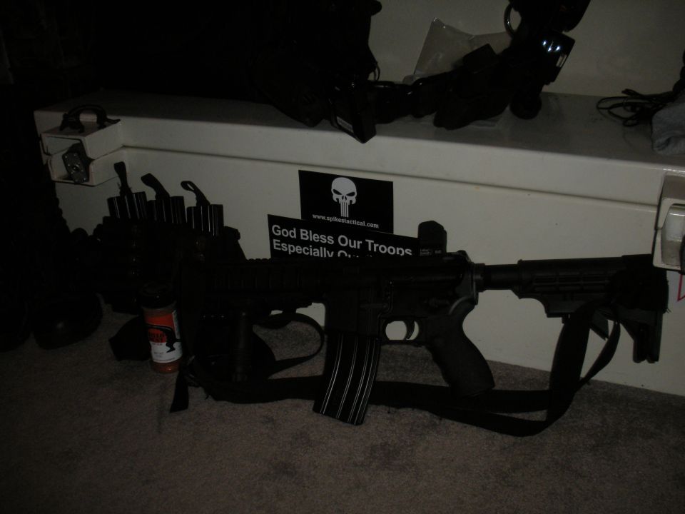 Assault rifle with loaded magazine and tactical gear, sticker reads 'God Bless Our Troops'
